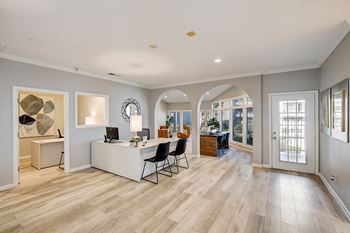 A spacious home office with a desk, chairs, and a large window.